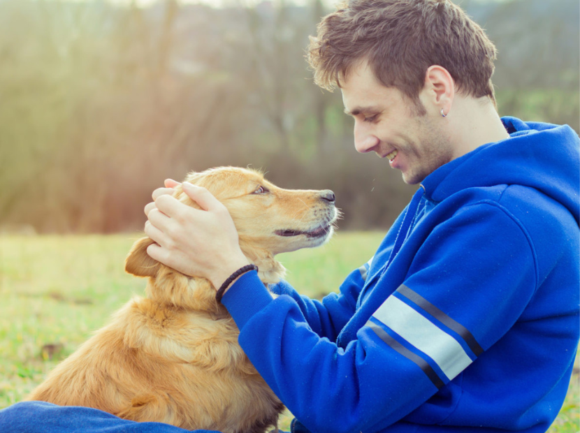 A man in blue shirt holding dog's head in hand